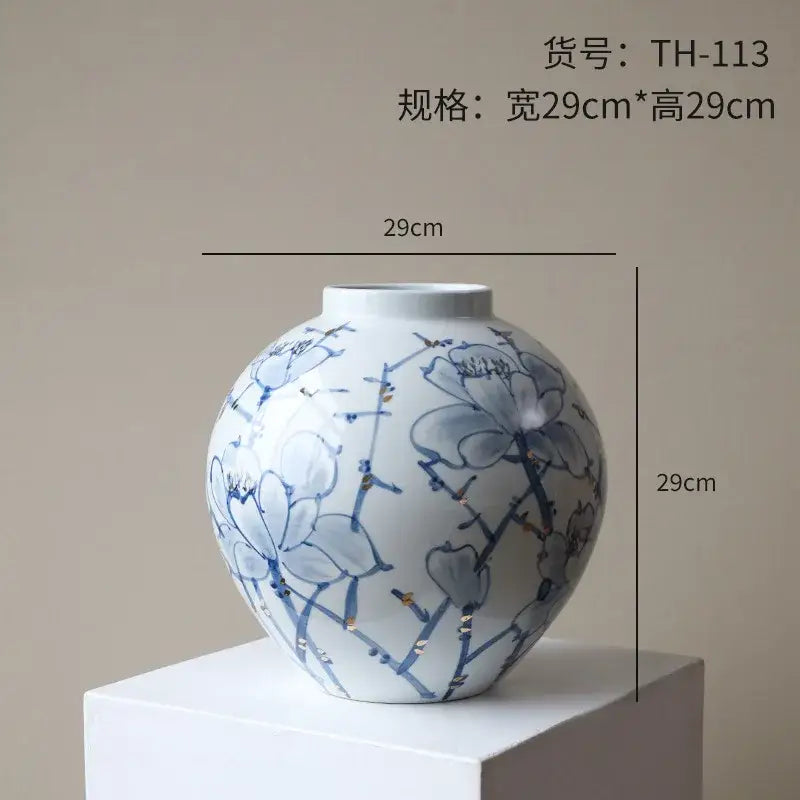 A round white porcelain ceramic vase with delicate blue floral patterns and gold accents for living room decorbites decor