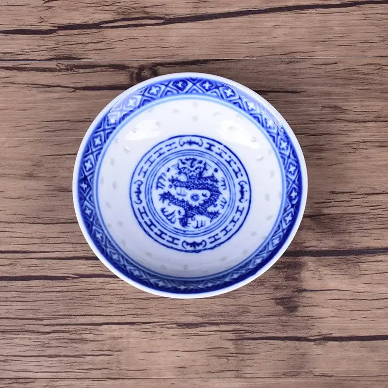 A white porcelain dragon tea bowl with intricate blue dragon pattern and geometric designs in a dish set