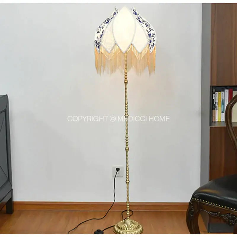 Elegant brass floor lamp with white porcelain floral lampshade and blue pattern featuring pearl tassel decor