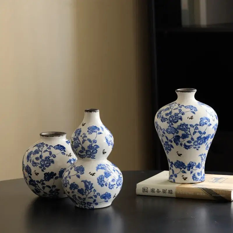 Three white porcelain gourd vases with blue floral patterns feature a traditional design and rustic finish for living room decor