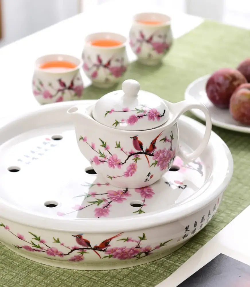 White porcelain tea pot set with pink cherry blossom and red bird motifs on a matching ceramic tray for dining room use