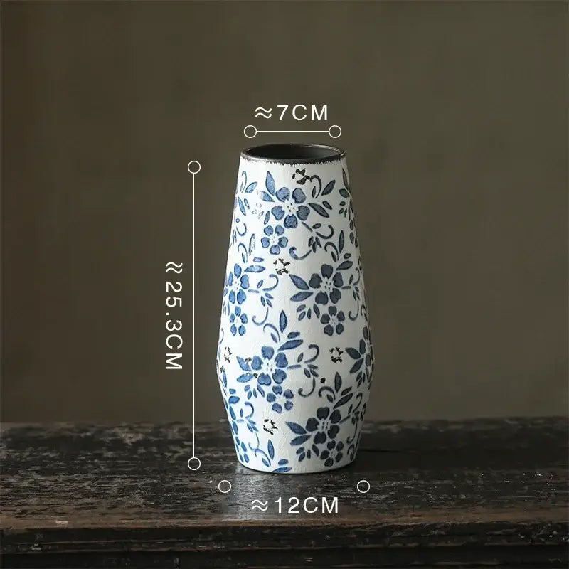 Slender white porcelain vase with delicate blue floral patterns and a dark rim for decorbites blue white decor