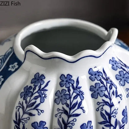 A white porcelain vase with scalloped rim and blue floral patterns in a porcelain vase desk set with artificial flowers