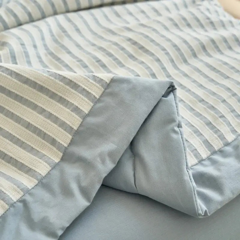 A soft quilted blue and white striped soya fibre decorbites jacquard summer quilt with subtle gray and cream tones