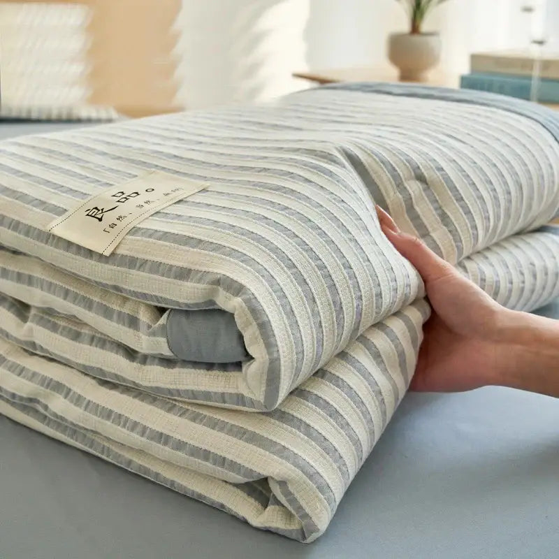 A neatly folded cream and gray striped decorbites jacquard summer quilt made of soya fibre with soft textured weave
