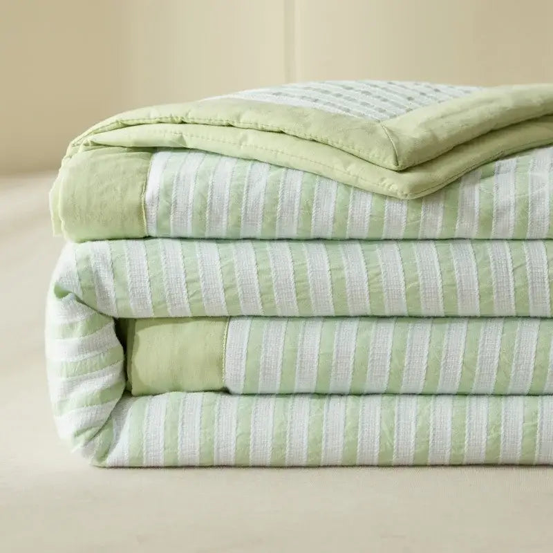 A neatly folded stack of light green and white striped soya fibre decorbites jacquard summer quilts for bedroom use