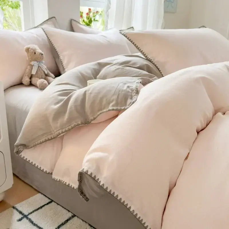 Soft blush and gray cotton bedding set with subtle zigzag stitch trim for a stylish bedroom look