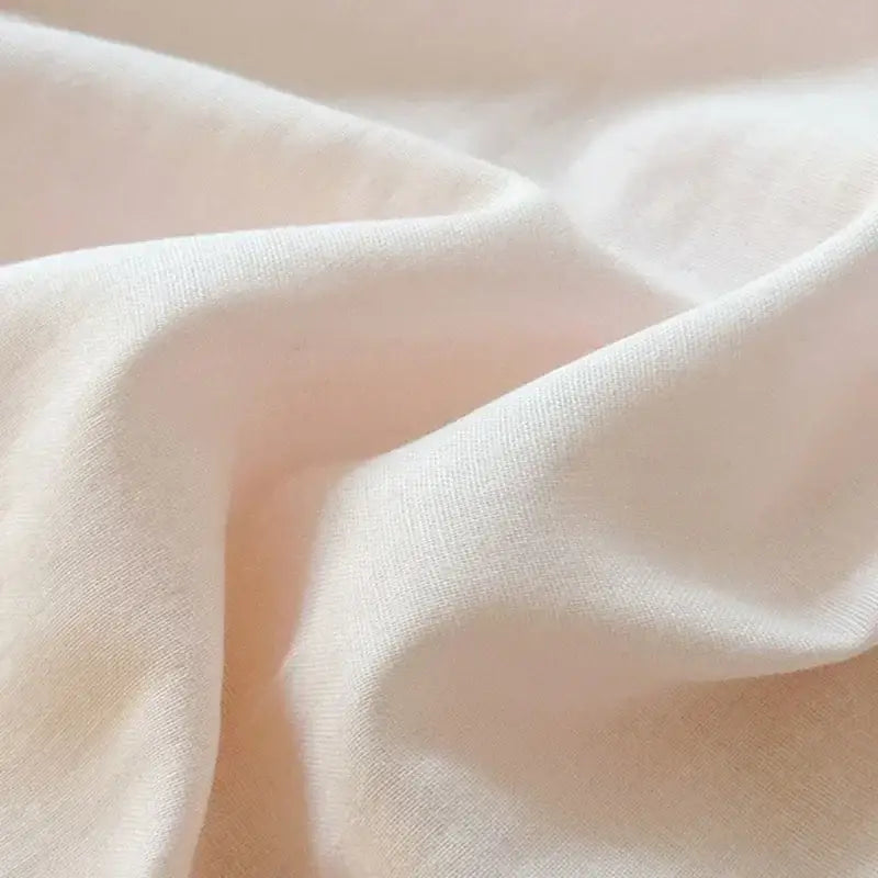 Soft off-white cotton fabric with subtle sheen and folds in blush pink and gray cotton bedding set with zigzag stitch cover