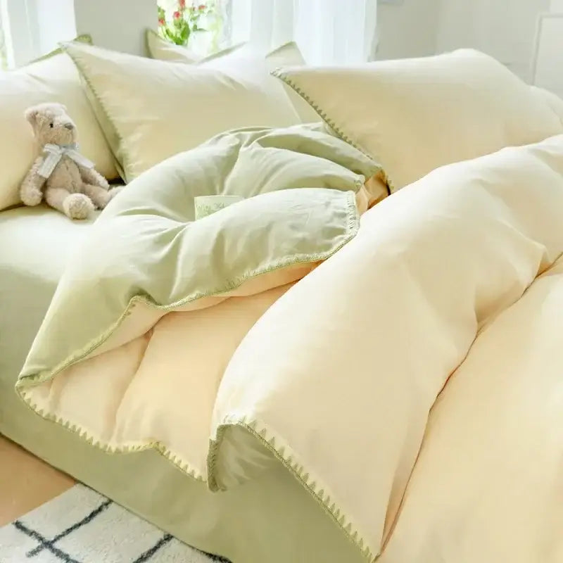 Soft cream cotton bedding set with mint green trim and stitched edge detailing in blush pink and gray cotton bedding