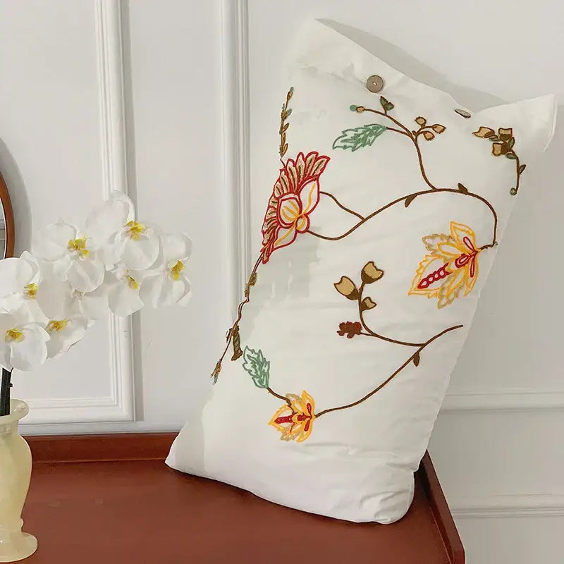 White cotton pillow with intricate red yellow green and brown floral embroidery from decorbites cotton bohemia bedding set