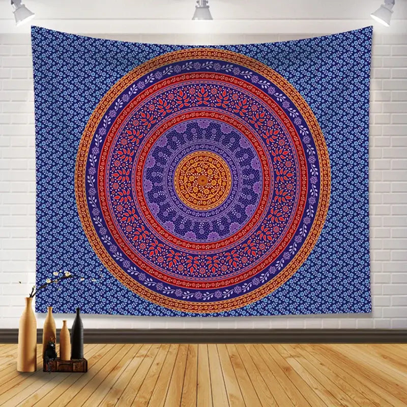 A vibrant blue bohemia room fabric tapestry with red purple and gold mandala patterns hanging on a white brick wall decorbites