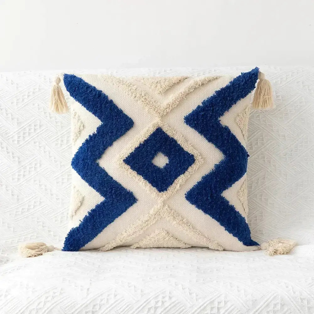 Cream-colored cushion cover with bold navy blue geometric patterns and bohemian tufted tassel decorbites design