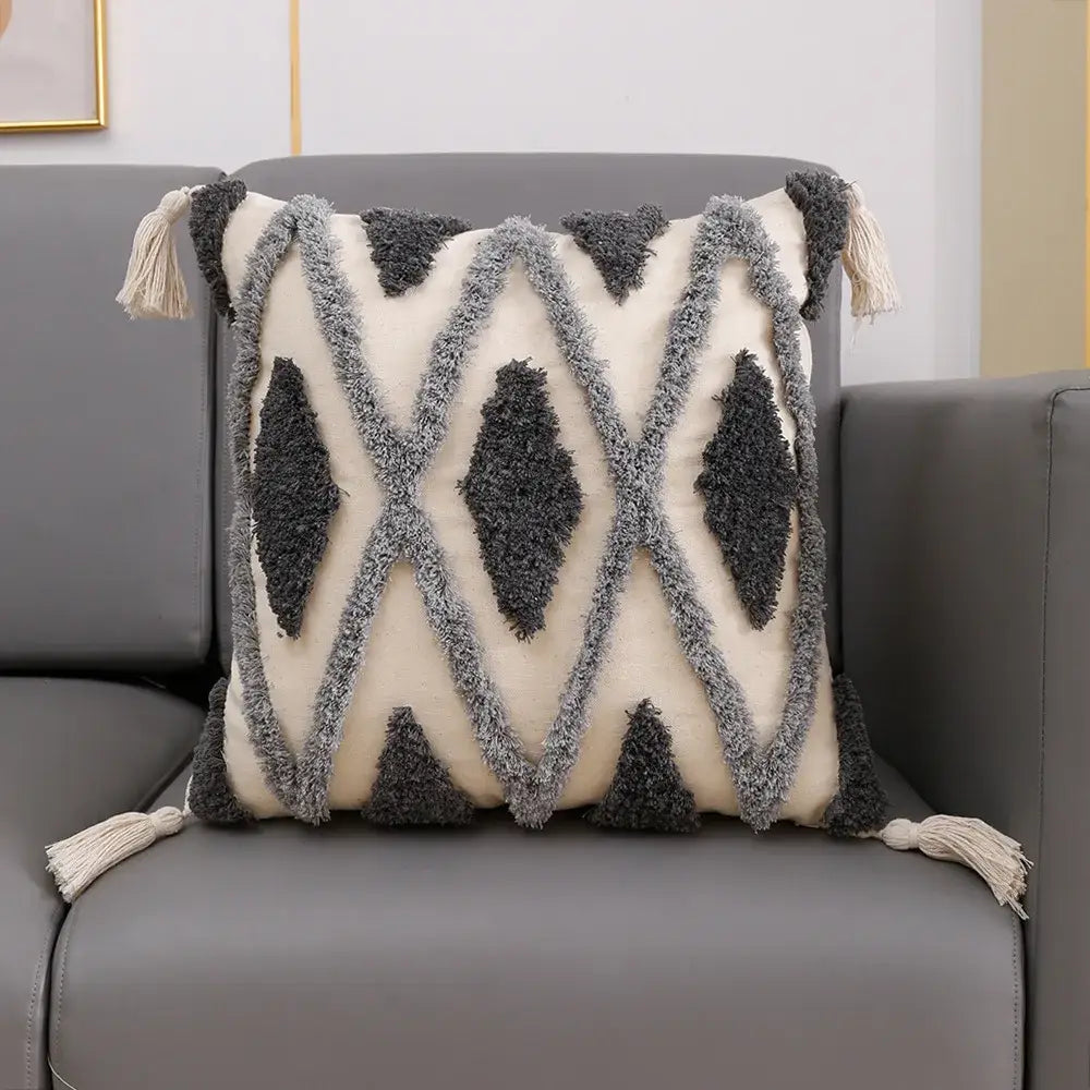 Cream-colored cushion cover with dark gray geometric pattern and bohemian tufted tassel accents for living room decorbites