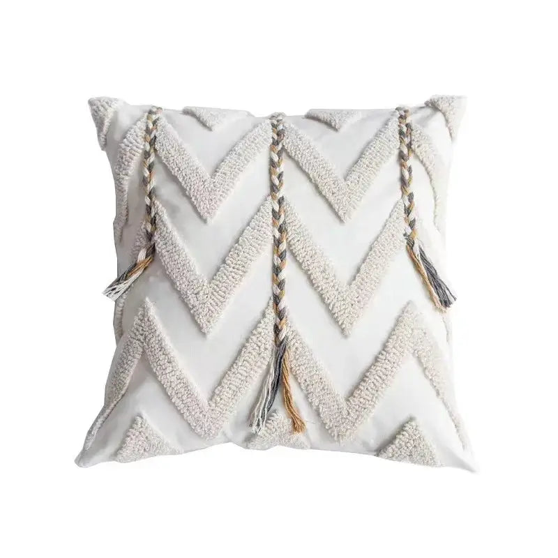 White square cushion cover with textured chevron pattern and three bohemian tufted tassel accents in beige and brown