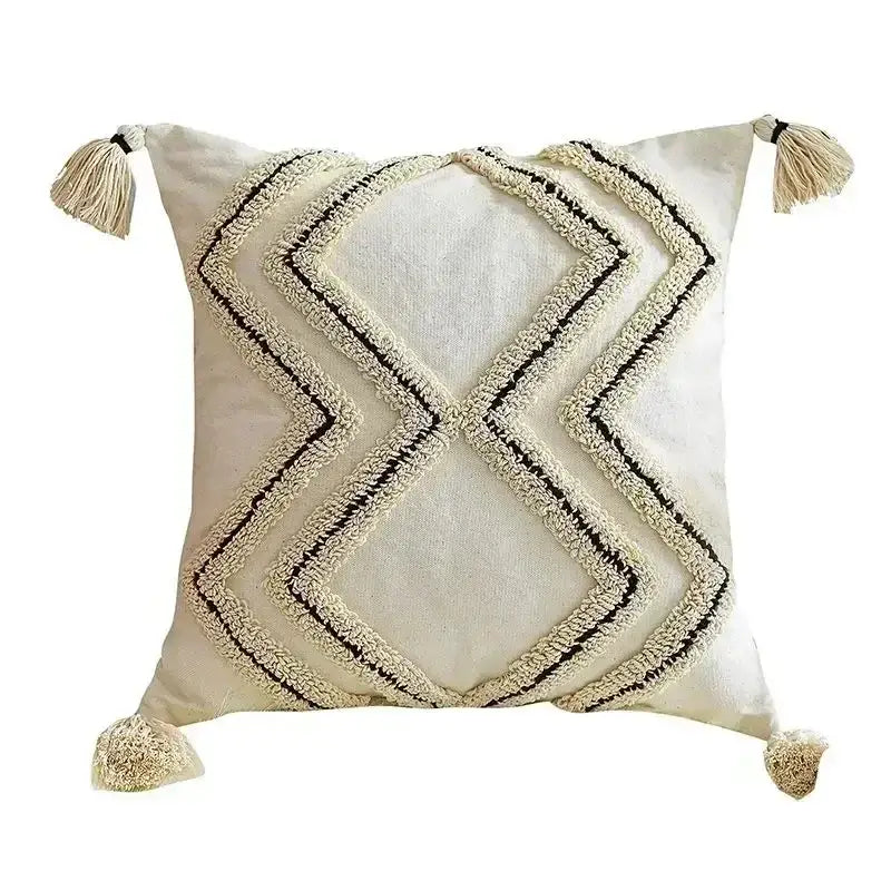 Cream-colored cushion cover with black and cream geometric embroidery and bohemian tufted tassel decorbites design