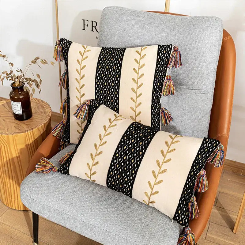 Two rectangular black and beige bohemian cotton embroidery cushion covers with gold leaf and colorful tassels for living room decorbites