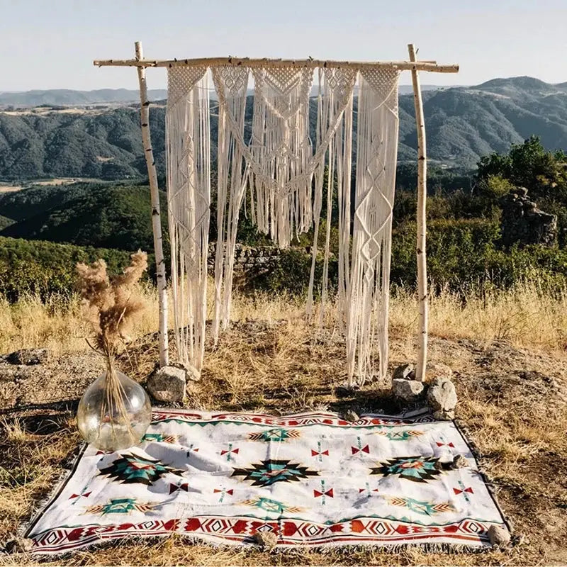 Cream-colored macramé wedding arch with intricate knotwork and tassels complements vintage plaid bohemian sofa blanket decorbites