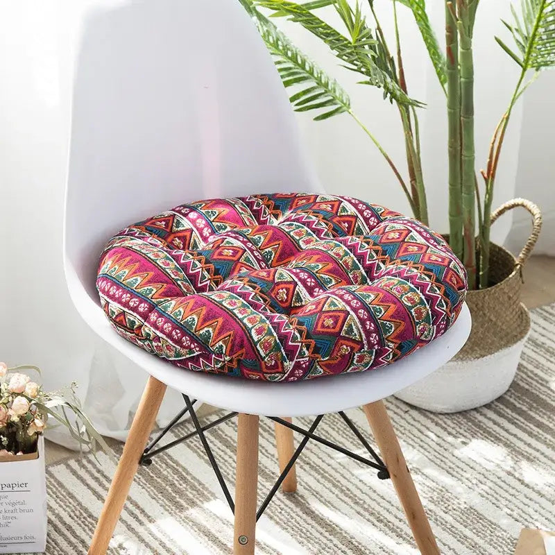 A vibrant bohemian meditation cushion pouf with blue green and red geometric pattern on a white chair