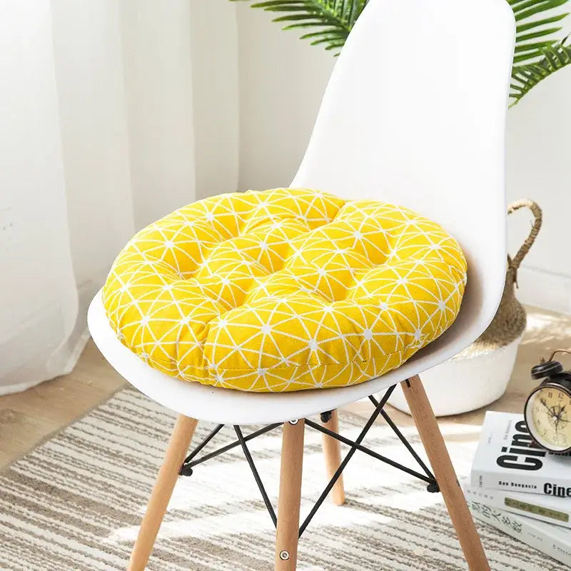 Bright yellow circular cushion pouf with white geometric pattern and tufted design on a modern chair for meditation use