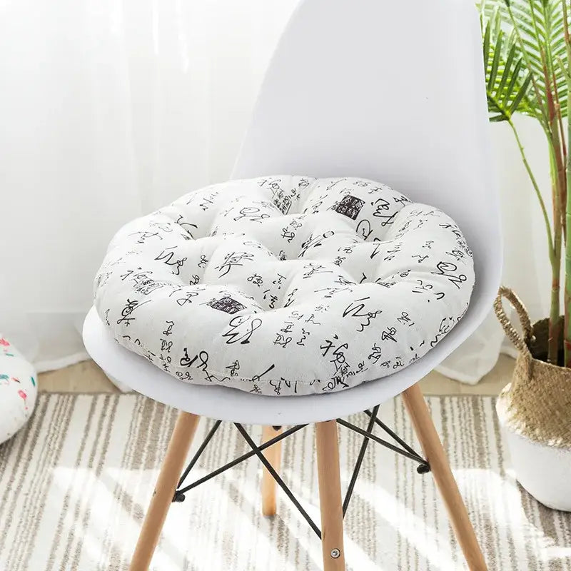 White circular meditation cushion pouf with black calligraphic script pattern tufted soft fabric for living room use