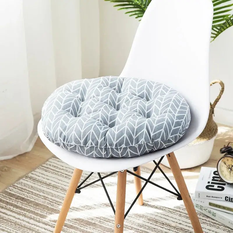Gray circular meditation cushion pouf with white geometric pattern and tufted design on a modern chair
