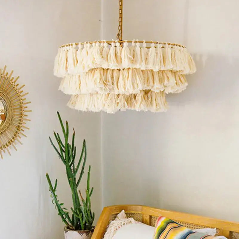A tiered off-white tassel light with gold suspension light chain and frame from decorbites bohemian chandelier collection