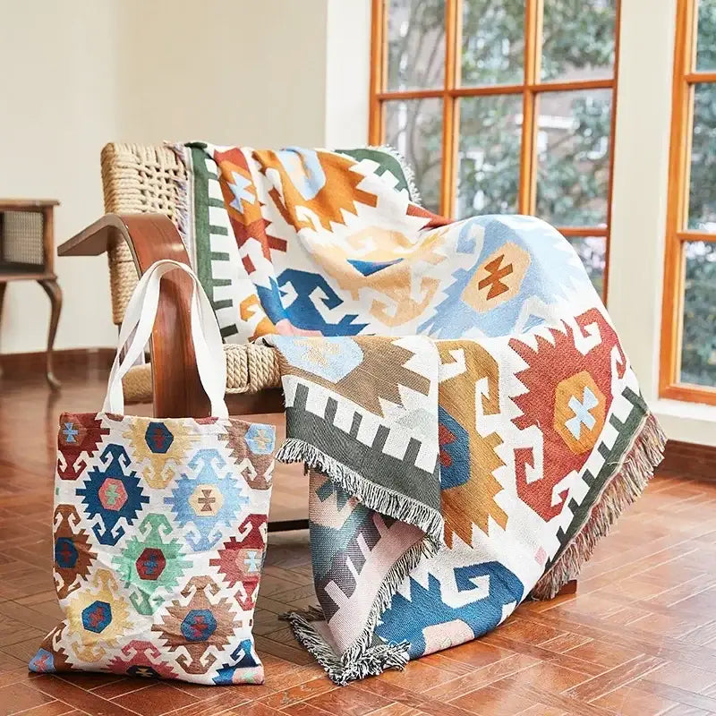 A decorbites bohemian classic woven throw blanket with vibrant blue orange red and beige geometric patterns and fringed edges draped over a wicker chair