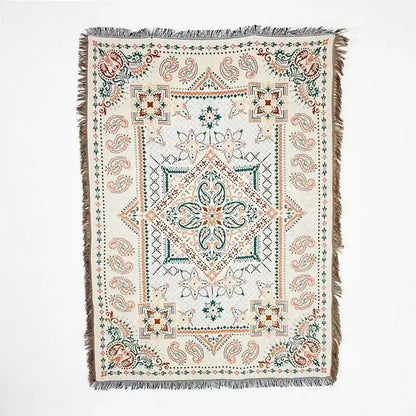A cream-colored woven throw blanket with pink geometric and paisley patterns and fringed edges decorbites bohemian classic