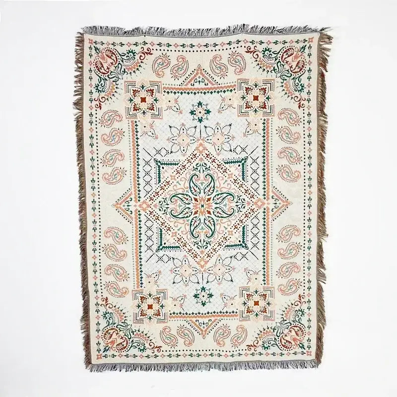 A cream-colored woven throw blanket with pink geometric and paisley patterns and fringed edges decorbites bohemian classic
