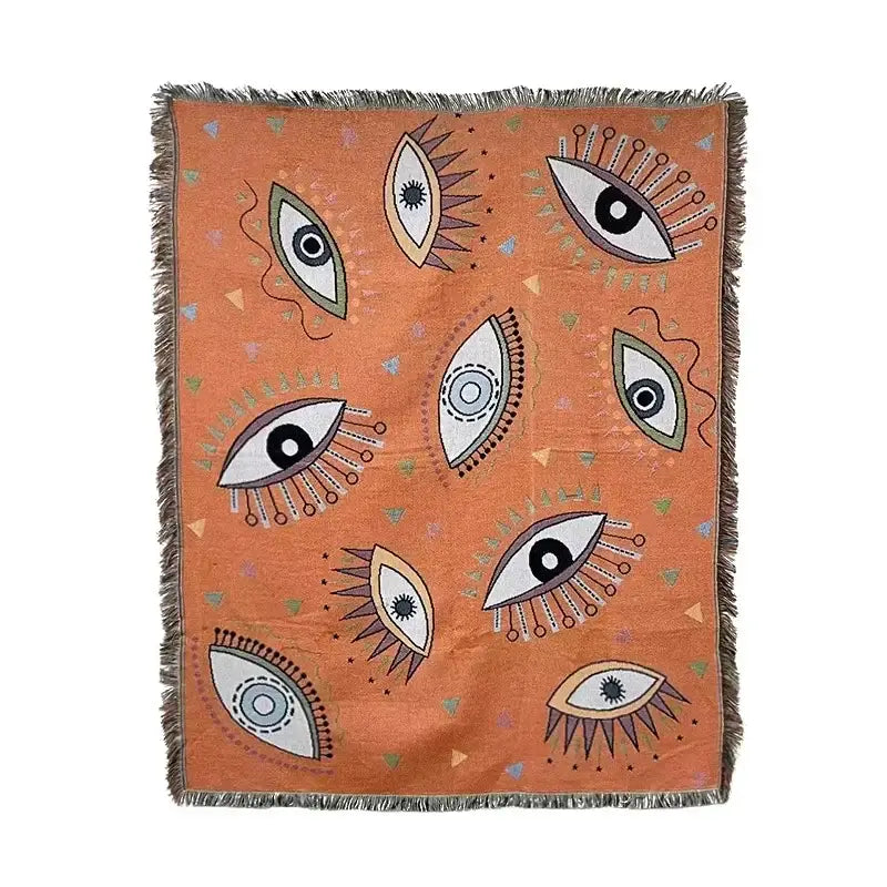 Orange woven throw blanket with stylized eyes pattern in black white and beige by decorbites bohemian classic design