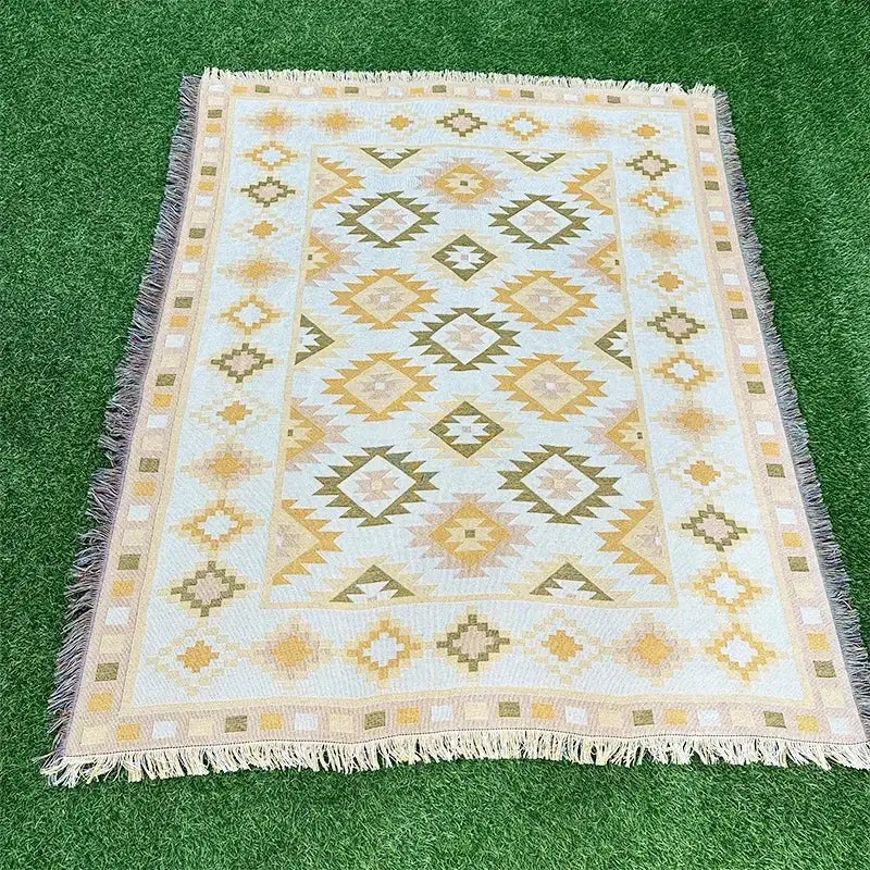 A cream-colored woven tapestry rug with yellow and olive geometric patterns and fringed edges in decorbites bohemian classic design