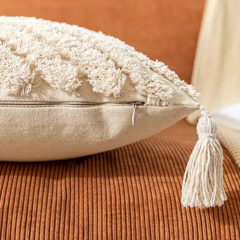Cream-colored bohemian cushion cover with textured tassel trim and fabric zipper tassel for living room decor by decorbites