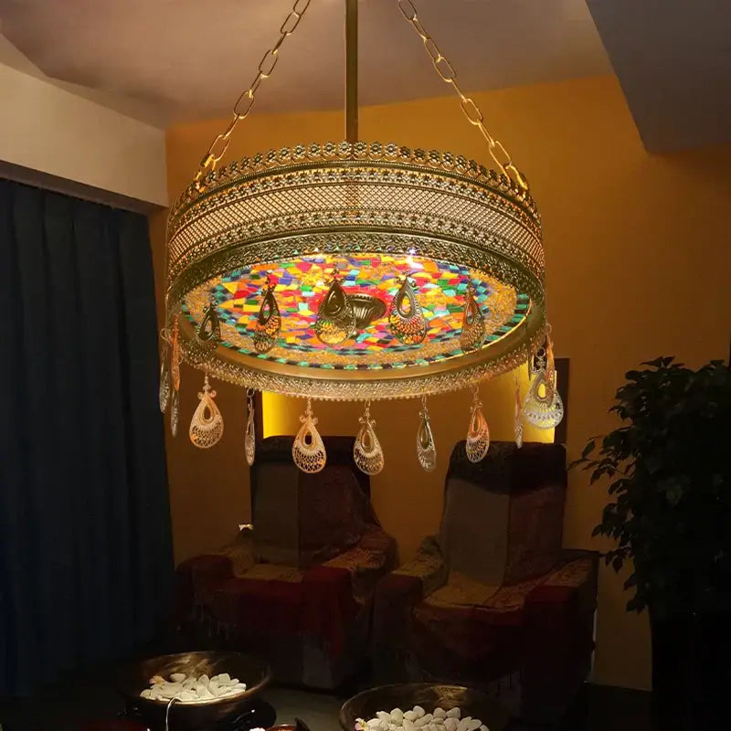 A golden ornate bohemian exotic stained glass pendant light with colorful mosaic center and teardrop metal pendants for dining room decorbites