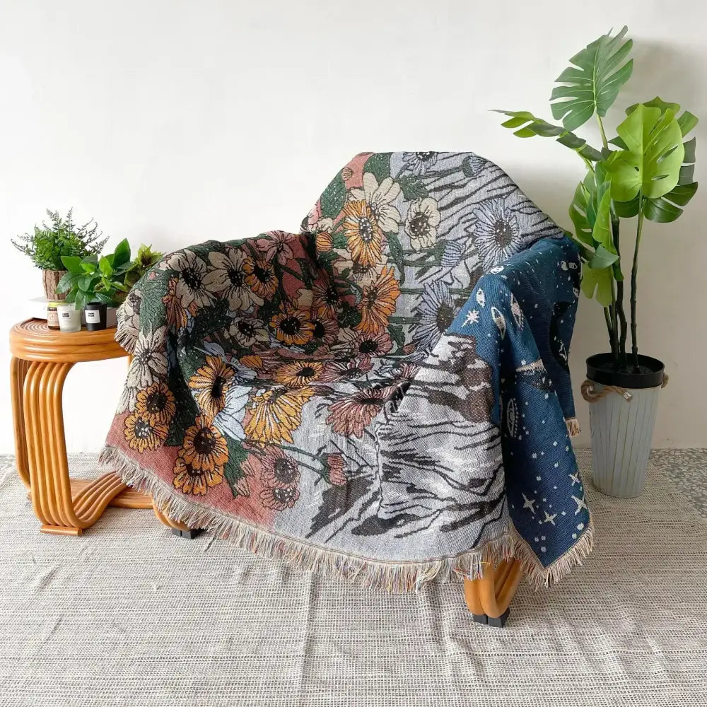 A cozy multicolored bohemian throw blanket with vibrant floral and celestial patterns draped over an armchair