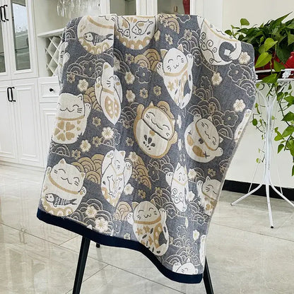 Gray cotton blanket with white beige lucky cat pattern and gold accents displayed on black chair for decorbites bohemian floral bath towel wrap
