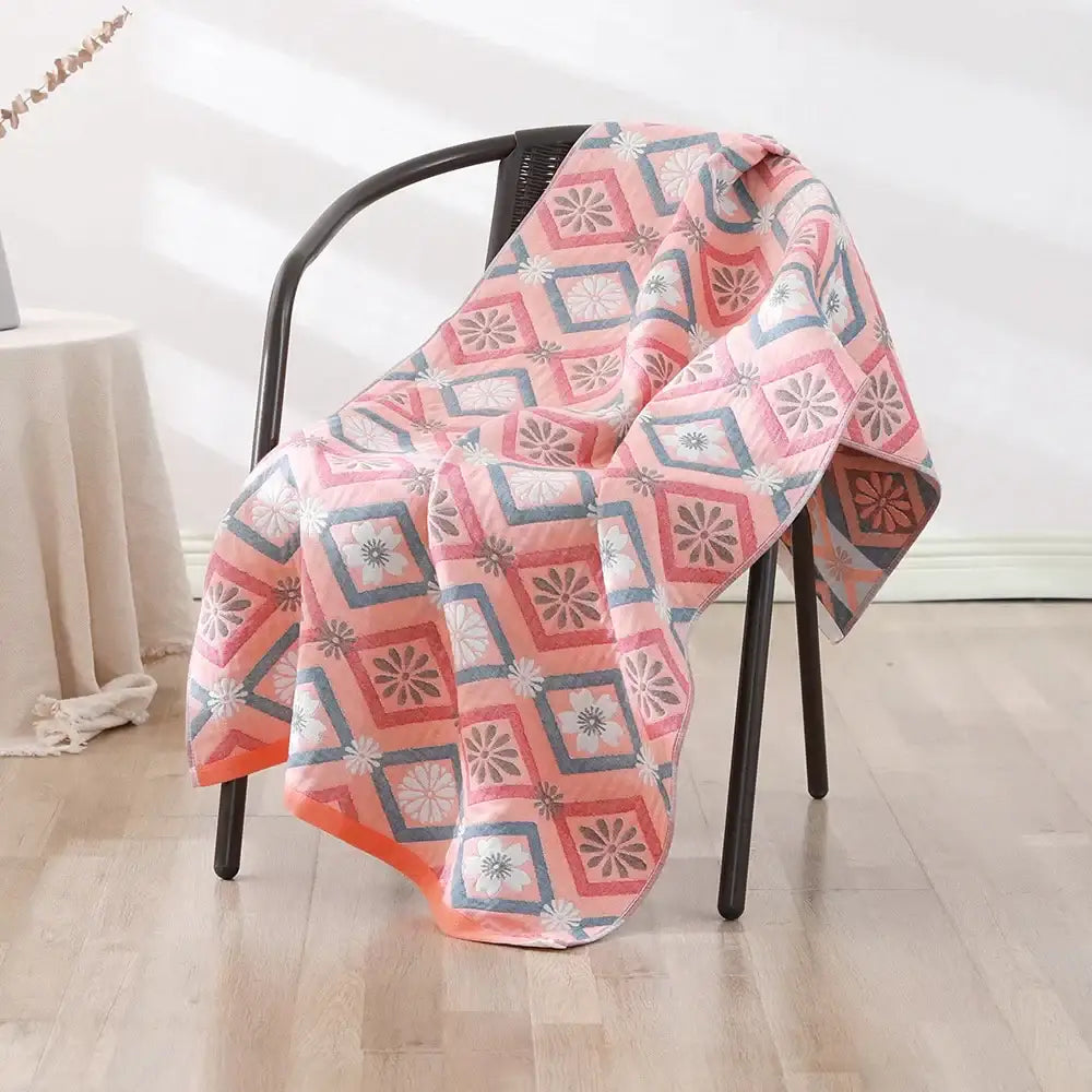 A soft quilted bohemian floral cotton bath towel in pink gray and white draped over a black chair decorbites bohemian floral