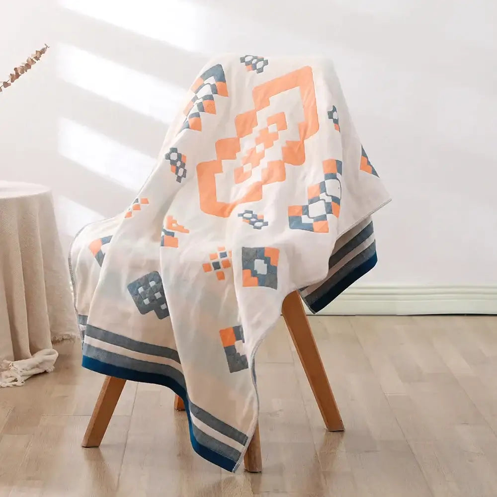 Soft off-white bohemian floral cotton bath towel with bold orange and navy geometric pattern and striped trim by decorbites