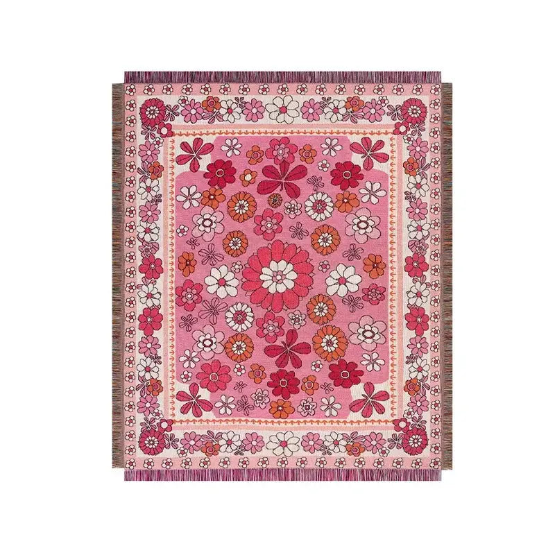 A vibrant pink bohemian floral leisure blanket with dense red white and orange woven pattern and decorative fringes for decorbites