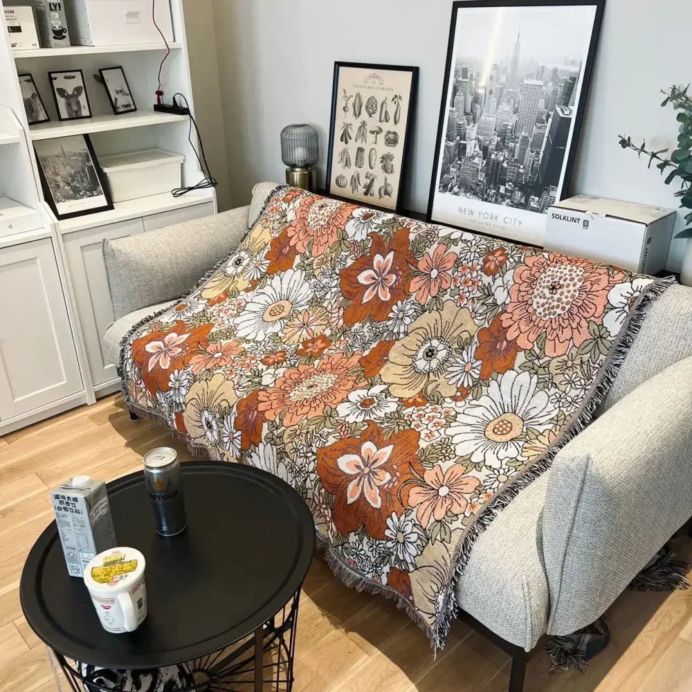 A cozy bohemian floral leisure blanket in rust and cream with vibrant orange floral pattern and fringed edges by decorbites