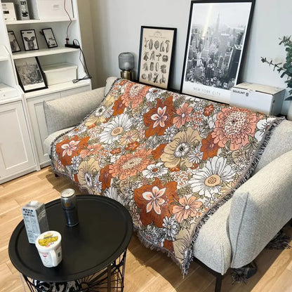 A cozy bohemian floral leisure blanket in rust and cream with vibrant orange floral pattern and fringed edges by decorbites