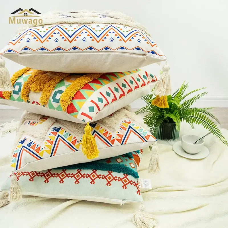 Stack of decorbites bohemian floral throw pillow covers with colorful geometric patterns and tassels on cream fabric