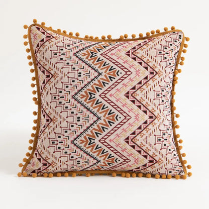 Beige square cushion cover with rust and black geometric patterns and mustard-yellow pom-poms decorbites bohemian flower