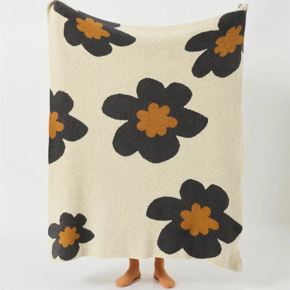Cream-colored plush bohemian flower knitted throw blanket with bold black and orange floral decorbites design for bedroom decor
