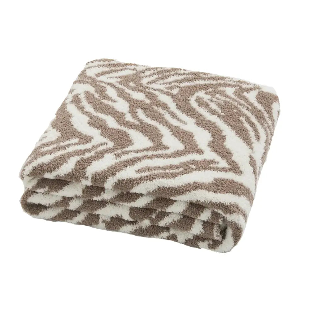 A plush beige and white zebra-striped throw blanket from decorbites bohemian flower knitted collection for bedroom decor
