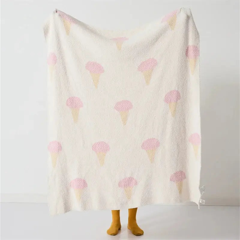 A cream-colored decorbites bohemian flower knitted throw blanket with plush texture and pink ice cream cone pattern