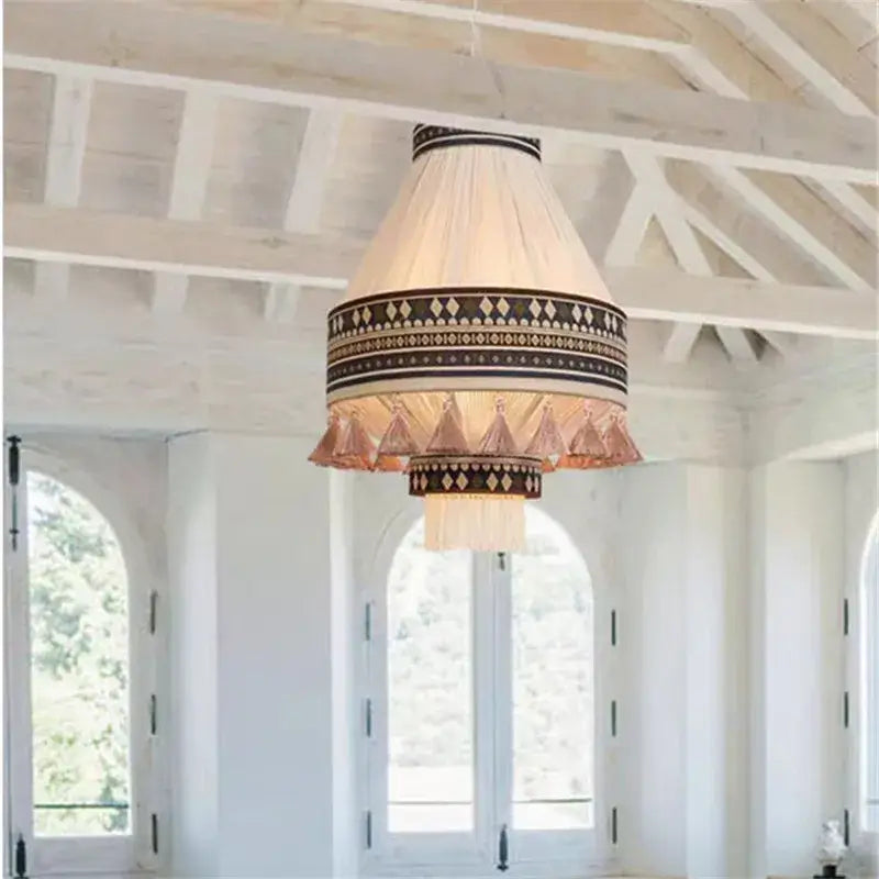Cream-colored bohemian fringe pendant lamp with black and gold geometric patterns and copper tassels for dining room use