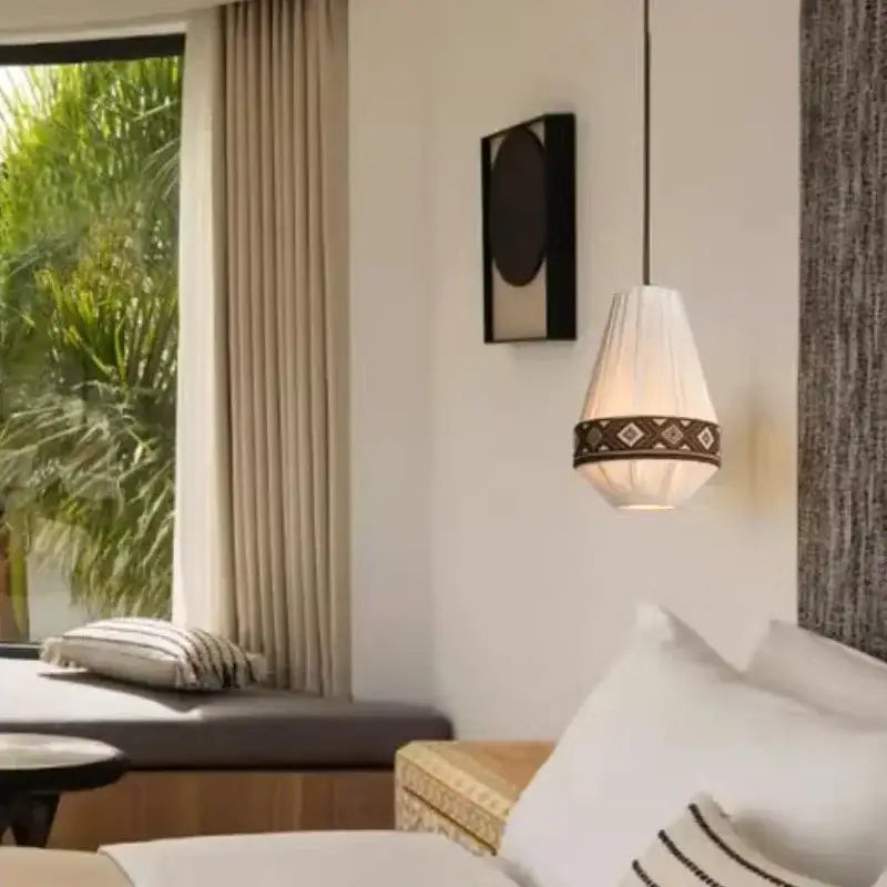A white bohemian fringe pendant lamp with a geometric patterned band hanging from the ceiling for dining room use
