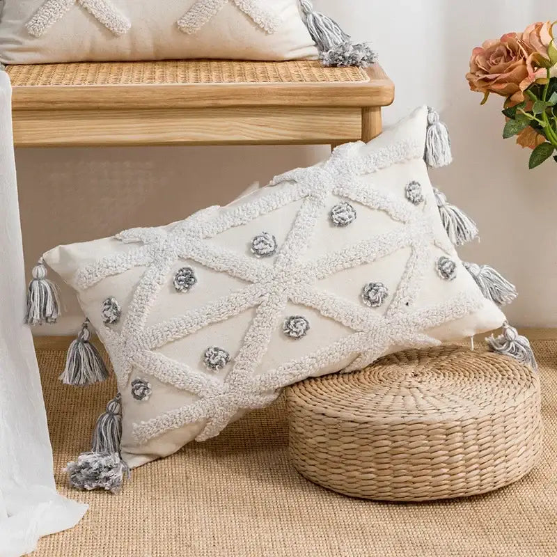 Cream-colored geometric tufted cushion cover with gray embroidered floral accents and textured white tassels by decorbites
