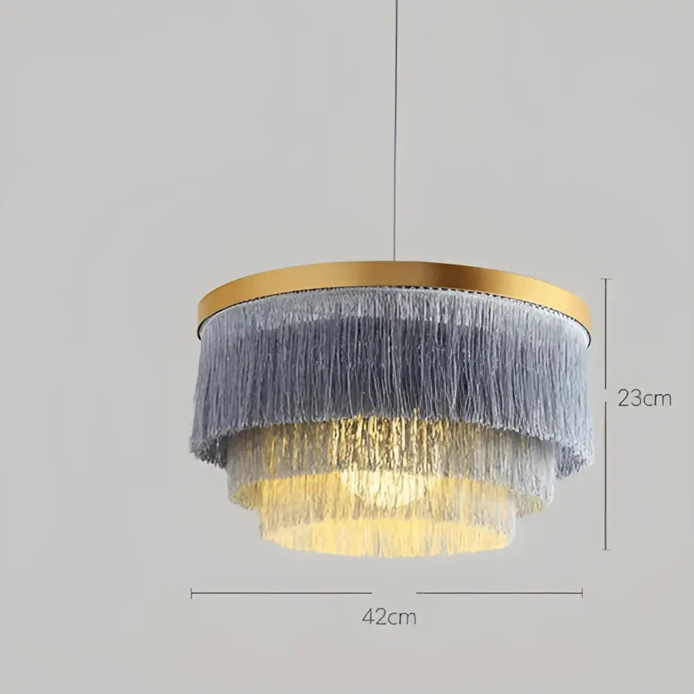 A modern bohemian gold tiered chandelier with cascading gray and golden fringe on a brass circular frame