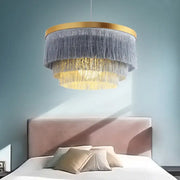 Bohemian gold tiered chandelier with gold-toned frame and cascading gray and golden fringes for bedroom decor